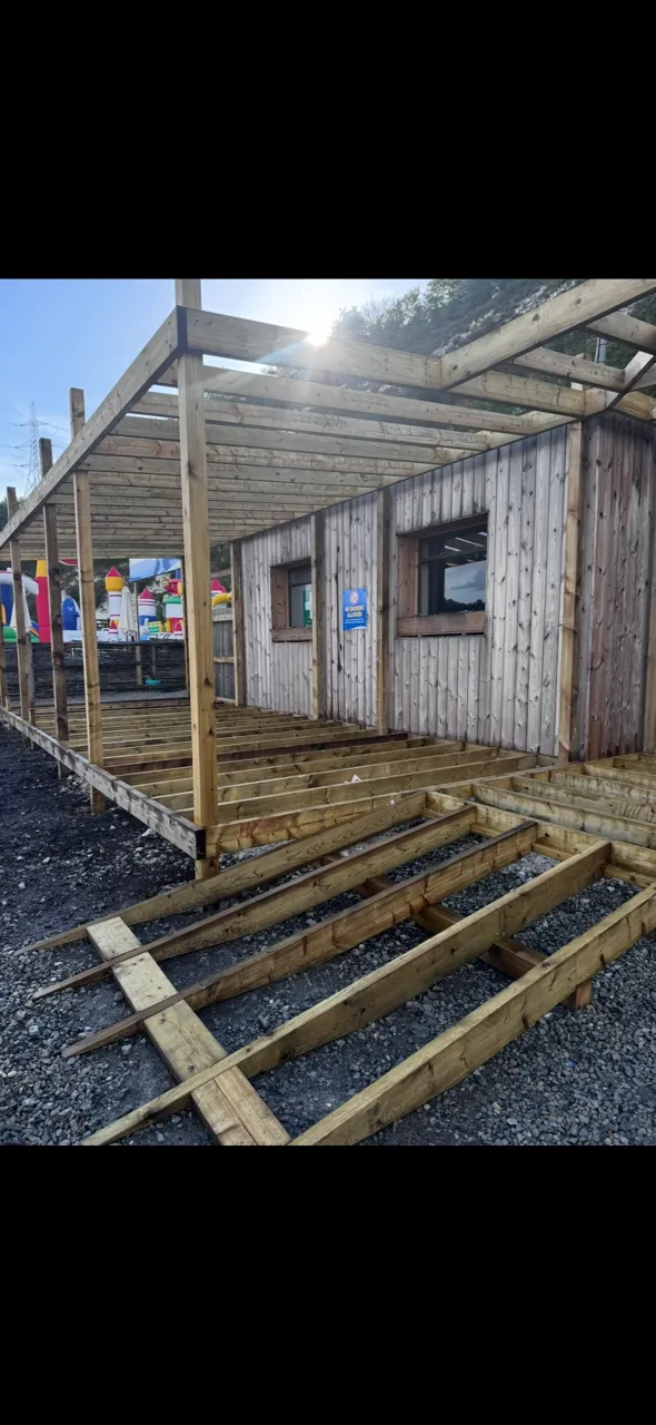 Timber frame carpentry under construction on site, with roof and wall framing taking shape