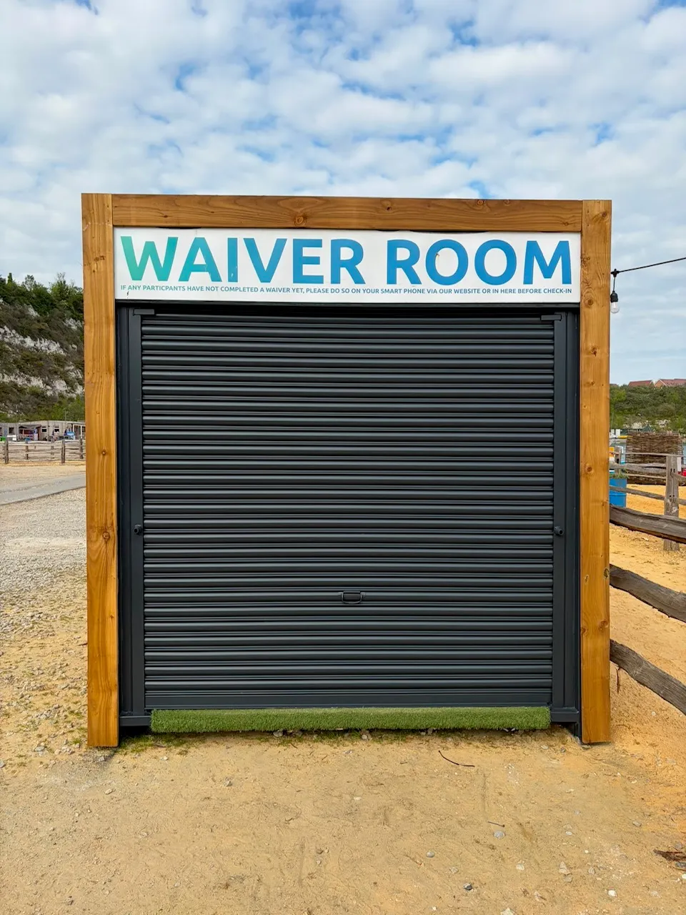 Timber-framed kiosk with a dark grey roller shutter, finished with an even airless-sprayed coating