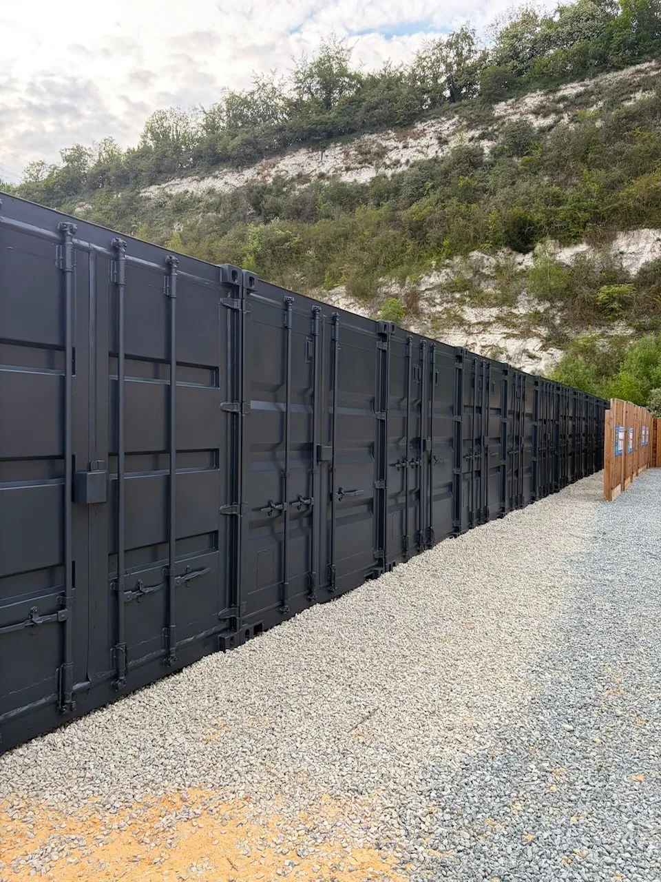 Tradesperson in full protective coveralls airless spraying a shipping container exterior