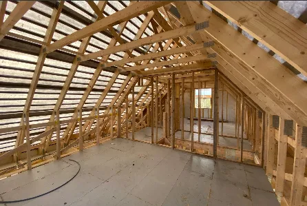 Interior view of a new build timber frame roof structure, showing exposed rafters and stud-wall framing