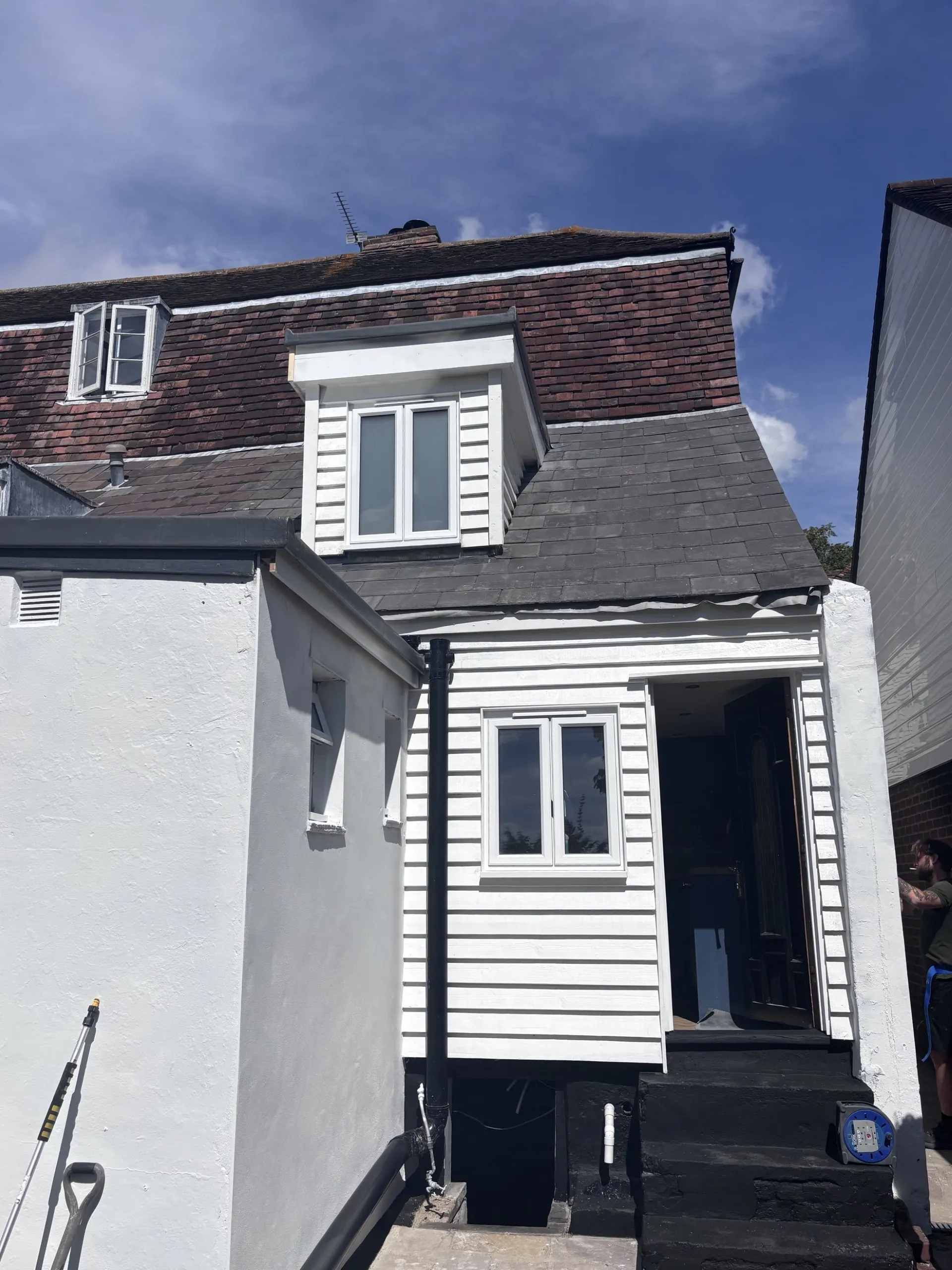 Rear extension with white weatherboard cladding and a dormer window, mid-refurbishment