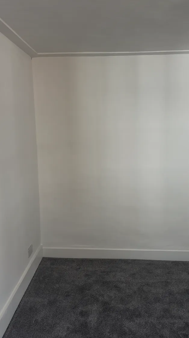 Freshly airless-sprayed white walls and ceiling in an empty room with grey carpet